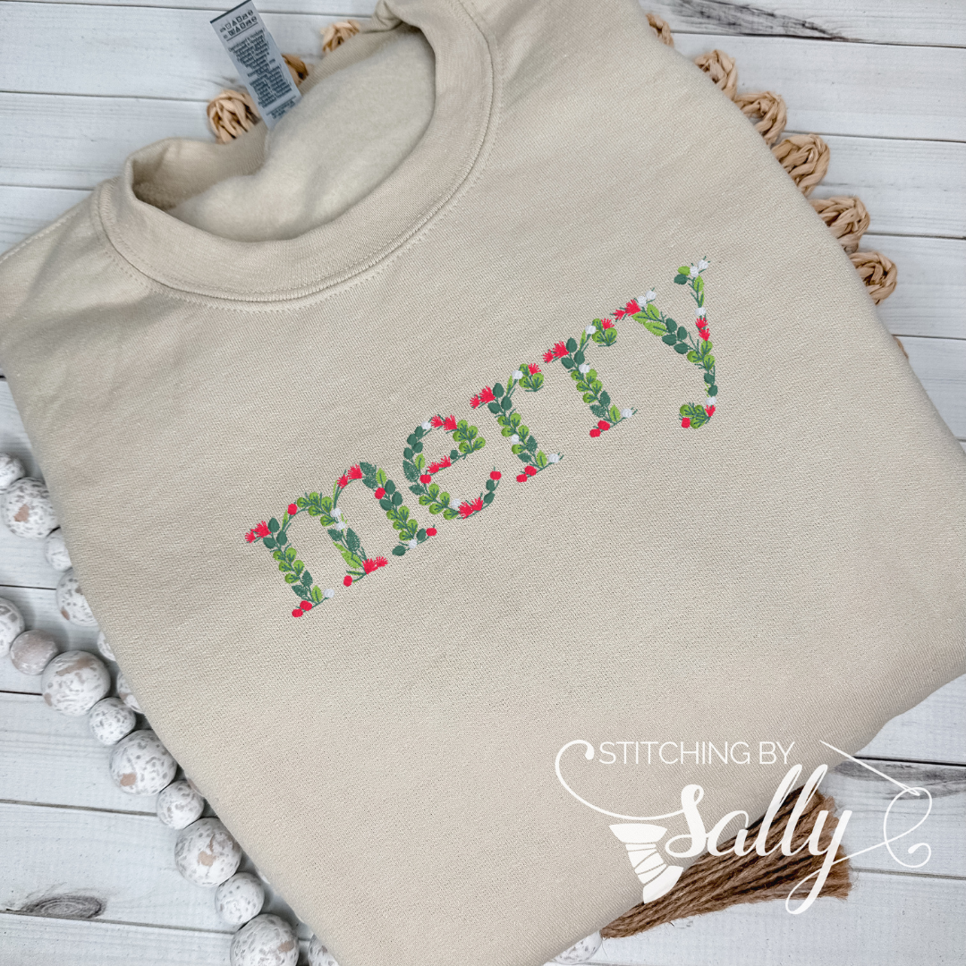 A cream sweatshirt with "merry" embroidered in festive leaves and berries font, perfect for adding a touch of cheer to your wardrobe. Stitching by Sally 