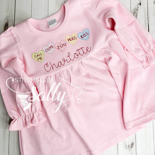 Pink tunic shirt with conversation hearts embroidered on it with a name.