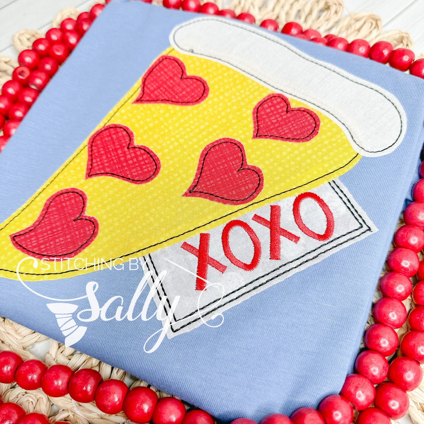 A blue shirt with a pizza appliqué design. Red hearts on pizza like pepperonis 