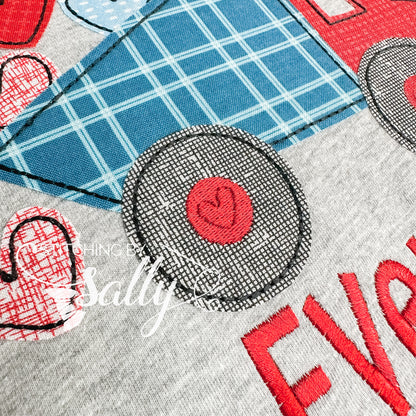 Up close picture of the embroidery detail of dump truck wheels. A heart is embroidered in them. 