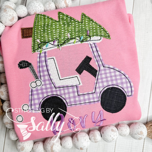 A toddler pink shirt featuring a golf cart appliquéd with purple gingham fabric decked for the holidays with a Christmas tree and Christmas lights on top.