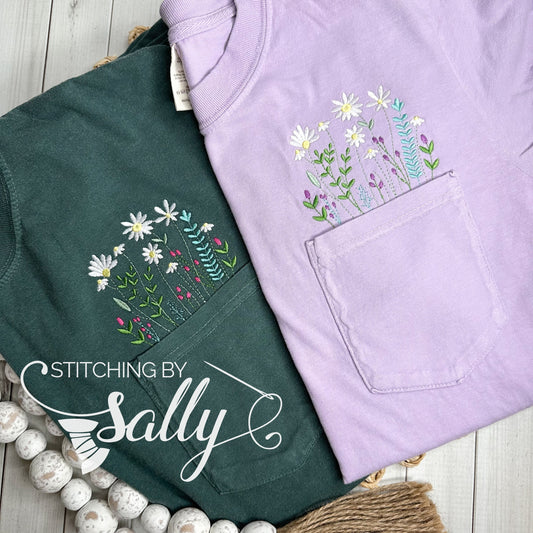 Wildflower embroidery above the pocket of a comfort colors shirt in lilac and blue spruce.