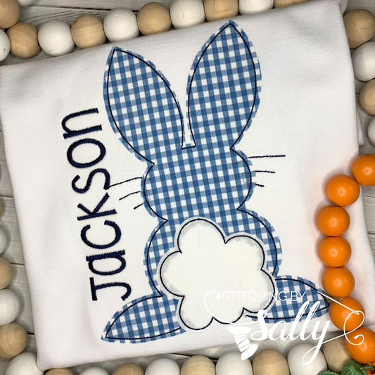 A white shirt featuring a blue gingham appliqué design of the Easter Bunny. 