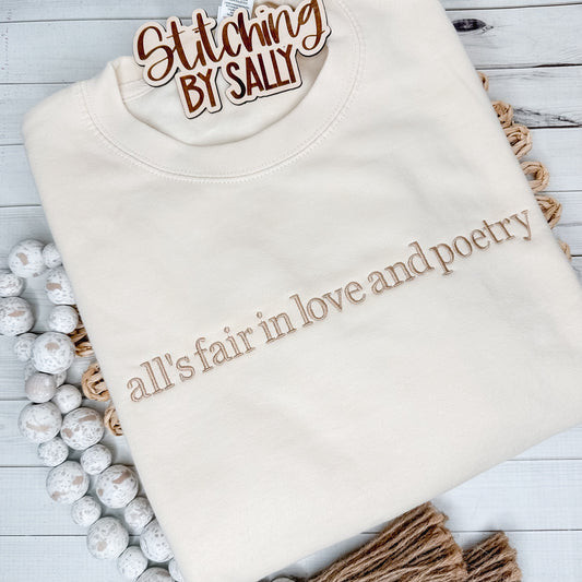 A cream crewneck with the words All is fair in love and poetry embroidered in a tan thread for a minimalistic look. 